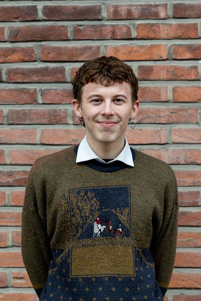 Magnus som smiler foran en murvegg