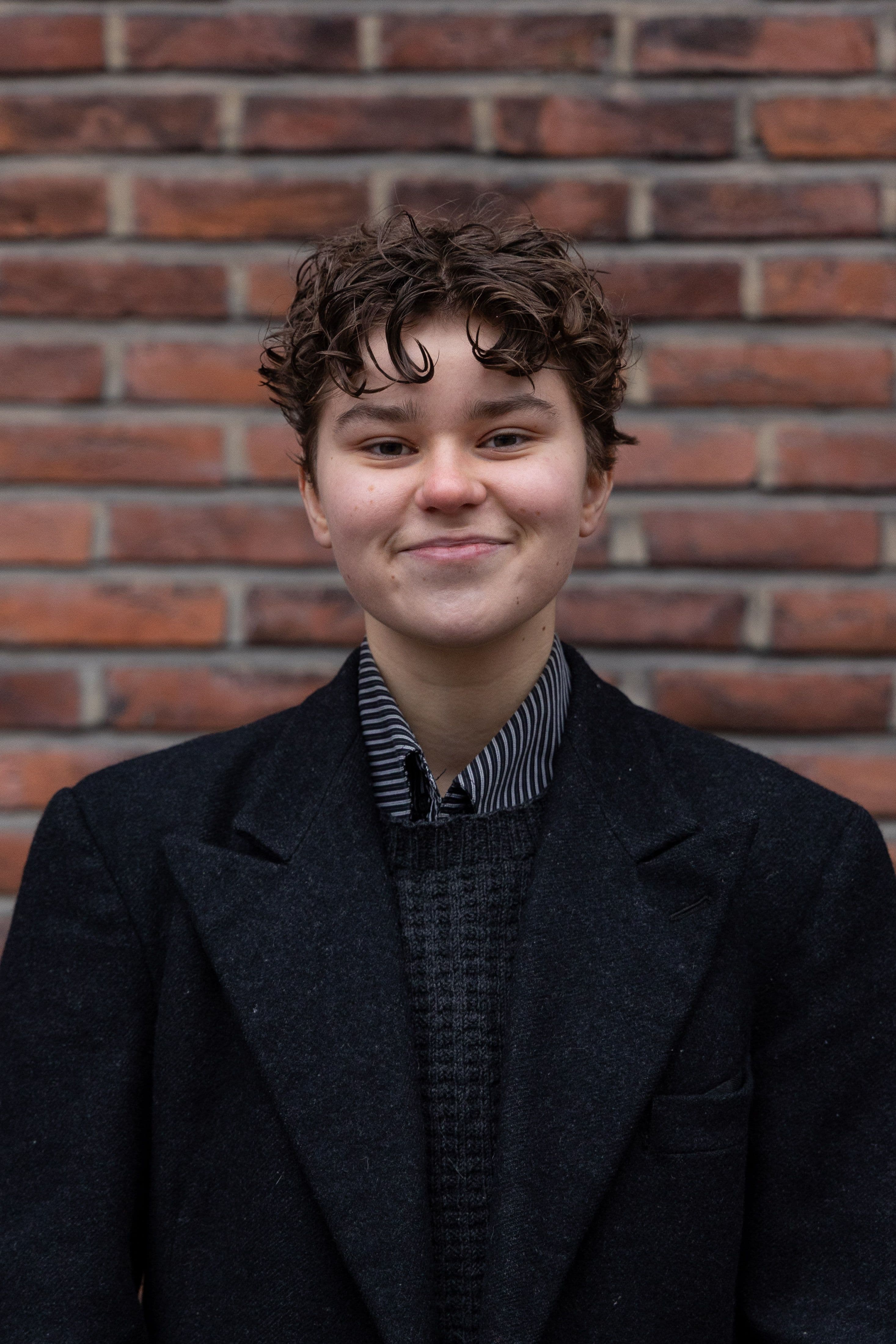 Person smiler foran murvegg