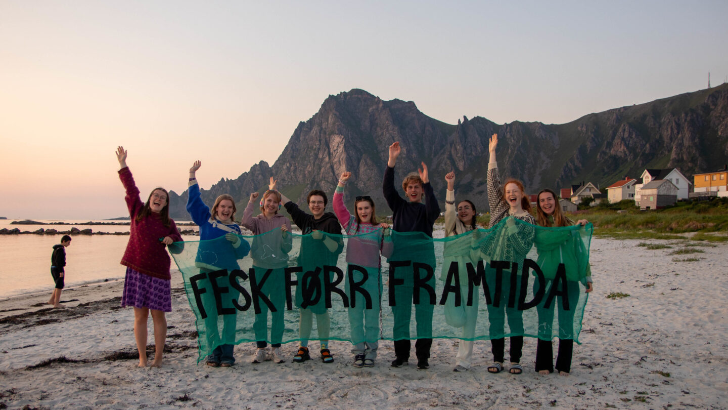 Ungdommer som jubler bak et banner hvor det står "Fesk Førr Framtida"